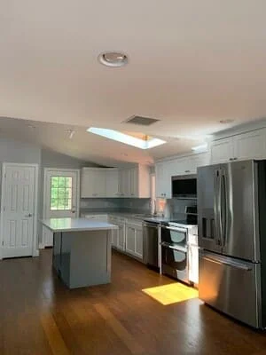 Gray kitchen cabinetry, stainless steel appliances, island with seating, hardwood floors