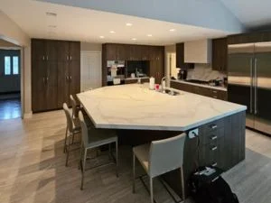 Modern kitchen with large white quartz island, dark cabinetry, and stainless steel appliances