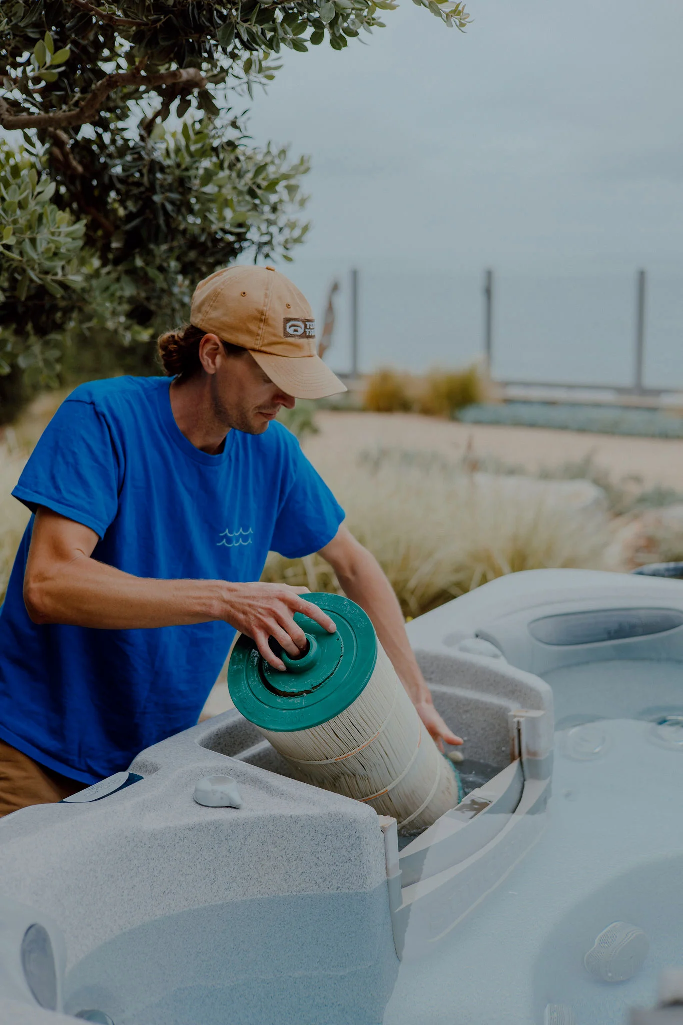 Technician replacing green filter cartridge on white hot tub with multiple units visible