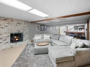 Sunken living room with gray sectional sofa, fireplace, and integrated spa installation with modern ceiling design