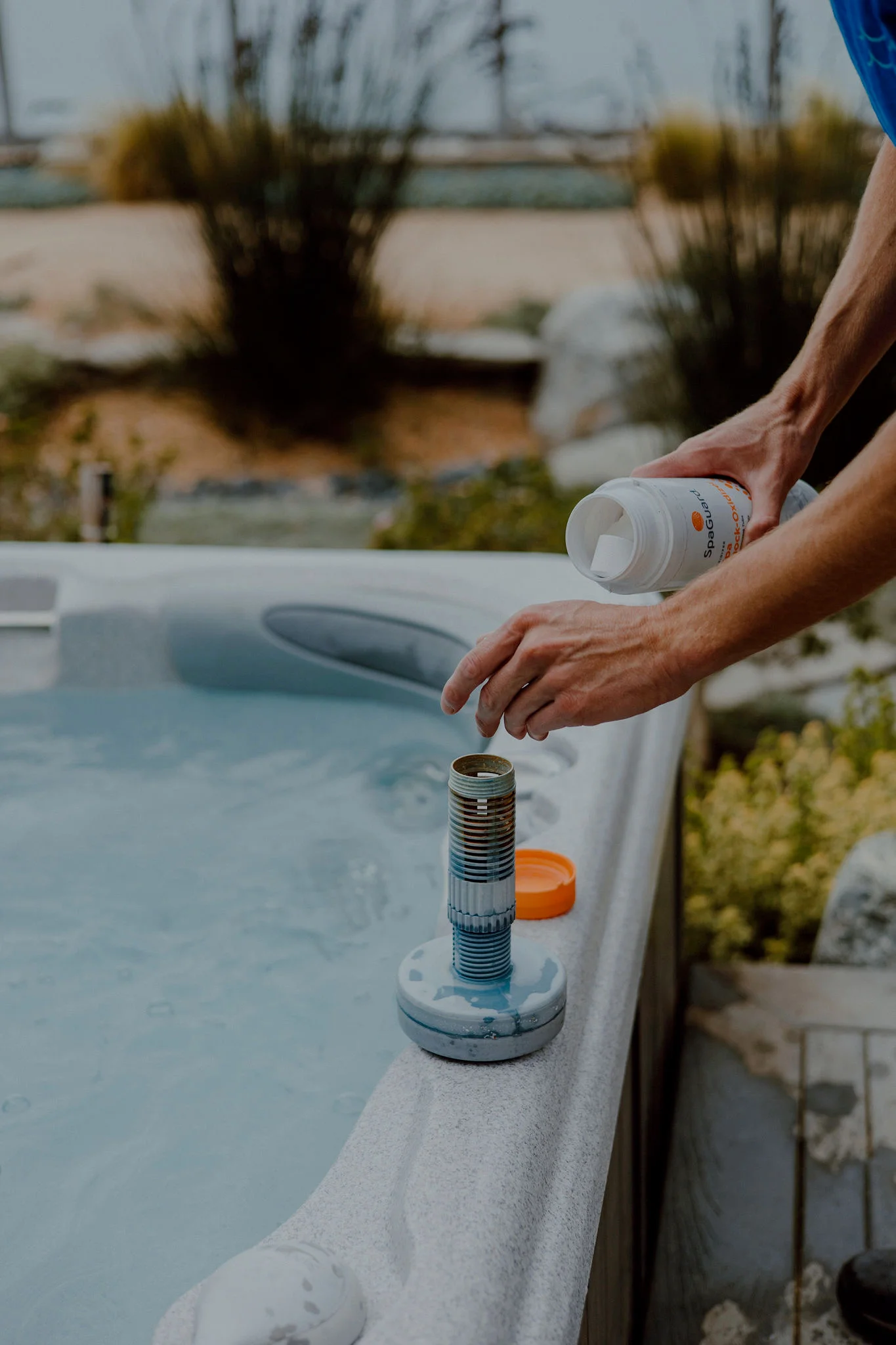 Technician applying spa chemicals through inlet valve with treatment container