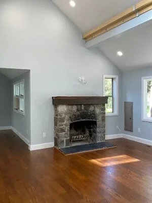 Stone fireplace with cast iron insert, slate hearth, and white drywall in residential living room