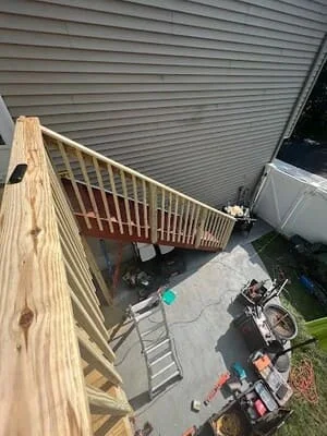 Pressure-treated wood deck with railings overlooking hot tub installation area and concrete pad