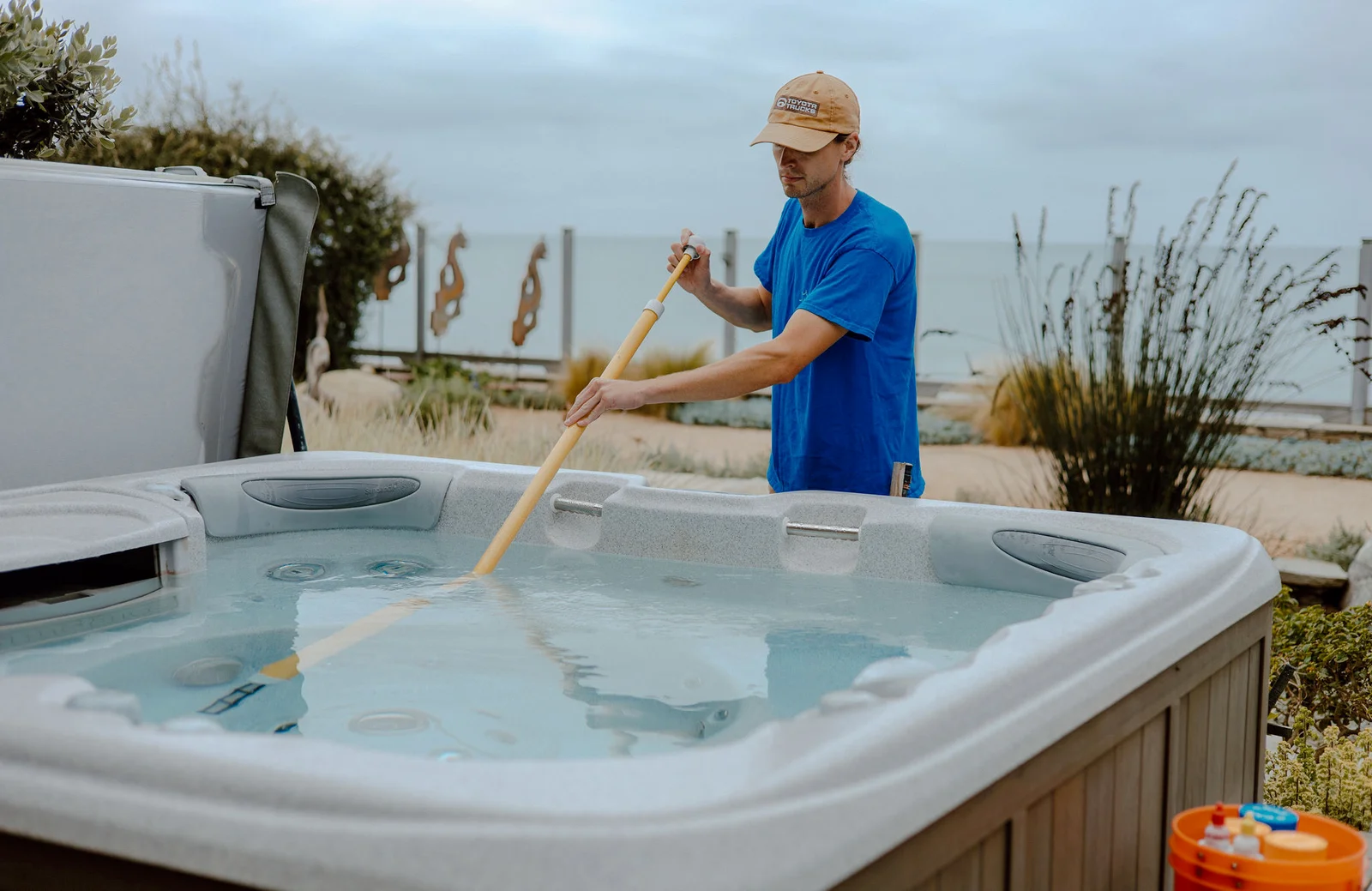 Technician using wooden brush to treat hot tub water during maintenance service